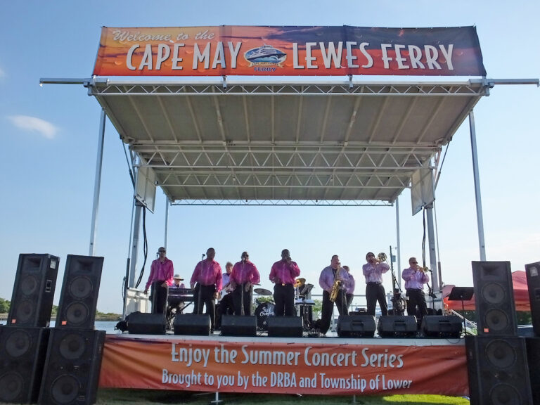 the Soul Cruisers (7 men in pink shirts and black pants) perform on stage at the Cape May Ferry terminal