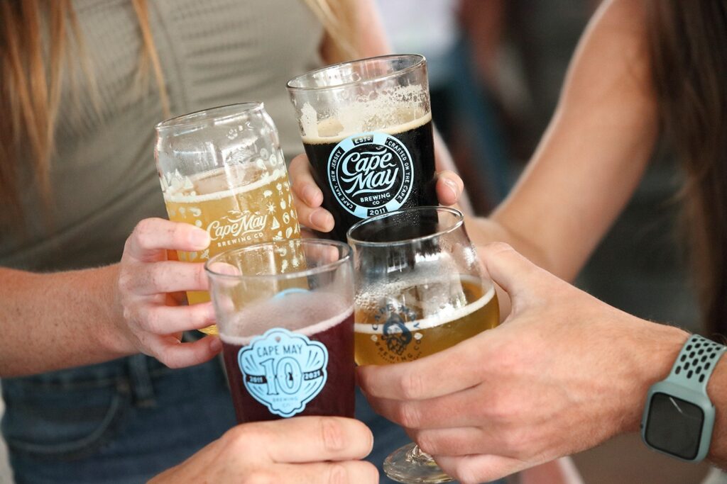 People's hands with 4 different varieties of beer from Cape May Brewing Company