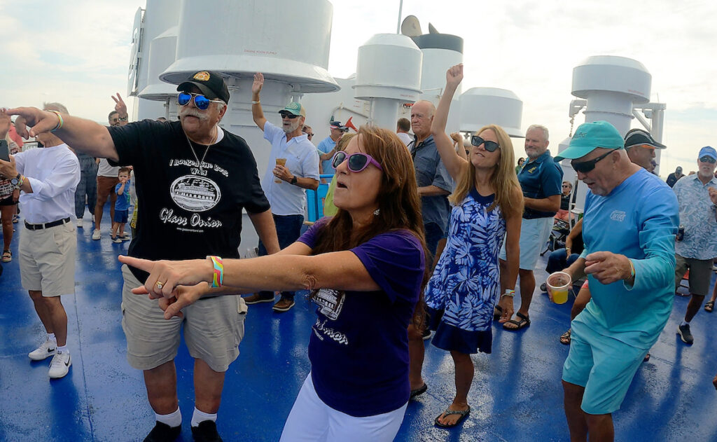 A lady in a purple shirt dances in the crowd during Rock the Boat