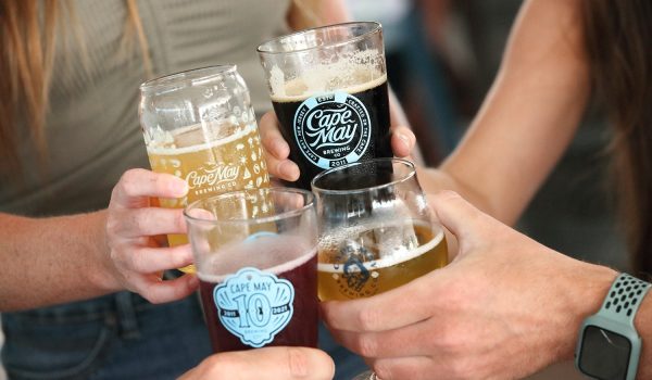 People's hands with 4 different varieties of beer from Cape May Brewing Company