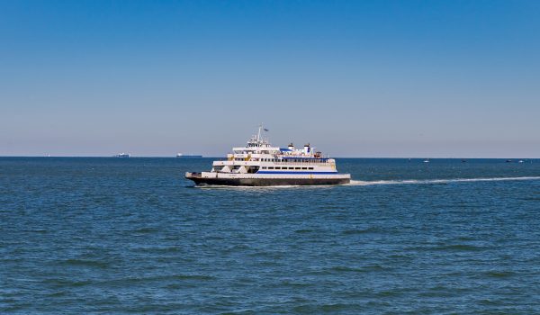 The Cape May - Lewes Ferry sails in the middle of Delaware Bay with freight liners visible in the distance on the Atlantic Ocean
